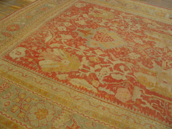 Low-pile rug with intricate red and beige traditional design on a dark wood floor.