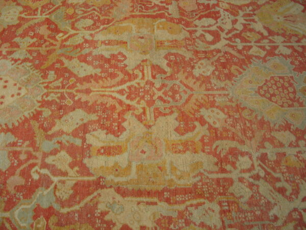 Low-pile rug featuring a distressed, stylized pattern in faded red, cream, and muted gold colors.