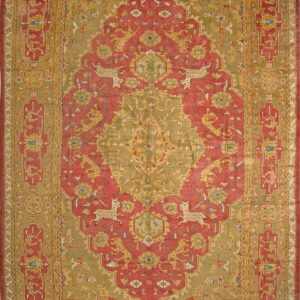Muted red and sage green rug with an ornate central medallion and stylized deer and lion figures.