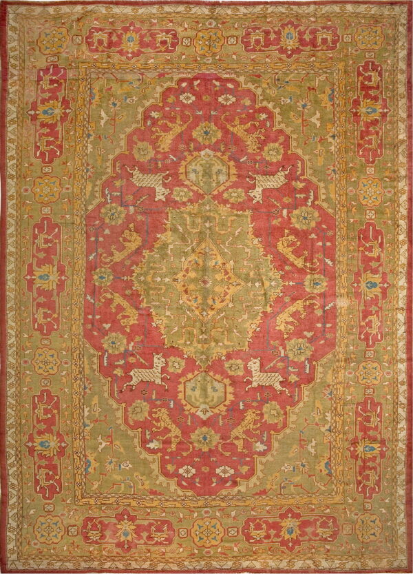 Muted red and sage green rug with an ornate central medallion and stylized deer and lion figures.