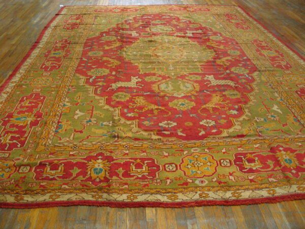 Ornate red and olive green rug features animal patterns, a central medallion, and detailed borders on wood planks.