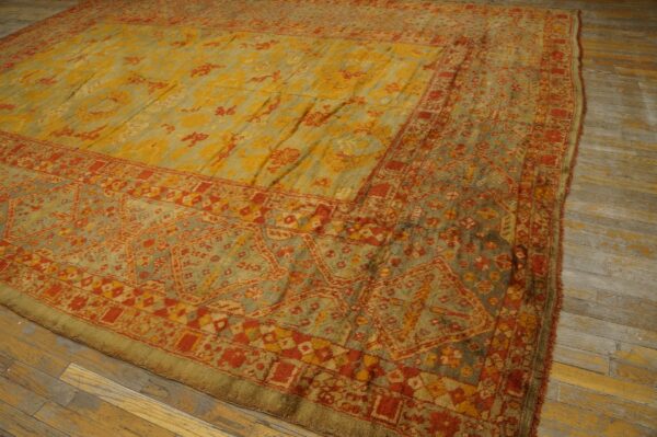 High-pile traditional rug with gold, sage, and terracotta colors lies on wide plank wooden flooring.