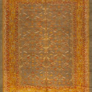 Muted gray rug featuring geometric tribal motifs and wide borders in gold and rust red.