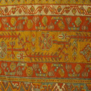 Striped rug detail showing orange, yellow, and gray geometric motifs against light plank flooring.