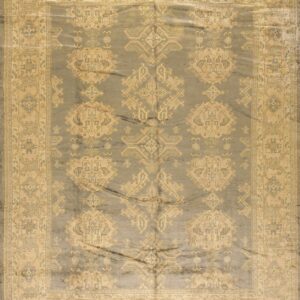 Dusty gray rug with low pile, featuring a beige traditional geometric pattern and wide, multi-layered border.