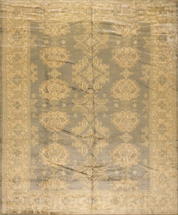 Dusty gray rug with low pile, featuring a beige traditional geometric pattern and wide, multi-layered border.