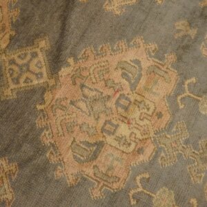 Muted gray rug featuring traditional motifs in soft peach, beige, and slate blue.