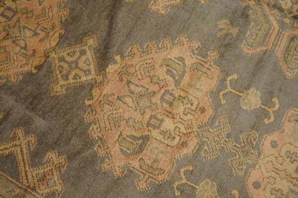 Muted gray rug featuring traditional motifs in soft peach, beige, and slate blue.