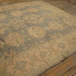 A large traditional rug with dusty sage and peach motifs rests on rustic wood plank flooring.