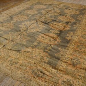 Low-pile traditional rug in dusky gray and gold geometric patterns rests on light wood floors.