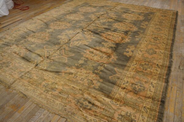 Low-pile traditional rug in dusky gray and gold geometric patterns rests on light wood floors.