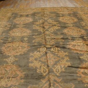 Muted gray-green rug featuring large orange and gold traditional medallions on light wood planks.
