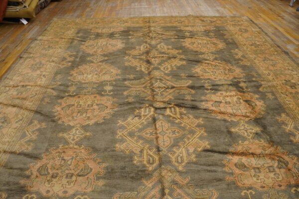 Muted gray-green rug featuring large orange and gold traditional medallions on light wood planks.