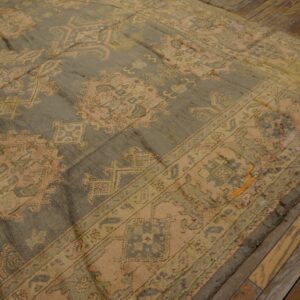 Muted gray and faded pink patterned rug with low pile lies on rustic hardwood planks.