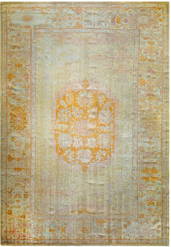 Traditional pale green rug featuring a prominent orange medallion and subtle floral borders on a washed field.