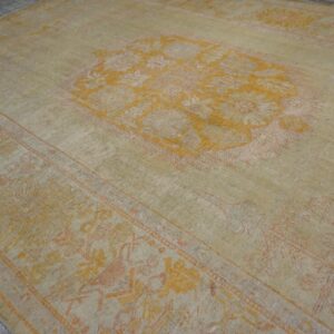 Low-pile rug with a faded beige and yellow floral medallion pattern on gray wood floor.