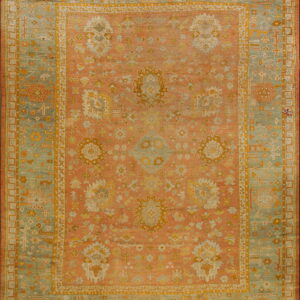 Ornate area rug with a coral field, a wide sage green border, and detailed geometric and floral patterns.