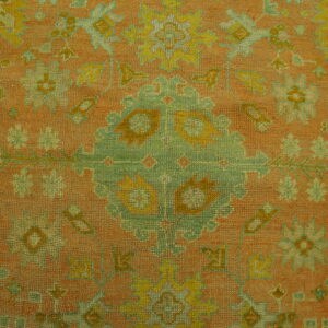 Low-pile rug detail showing a traditional medallion pattern in terracotta, sage green, and yellow.
