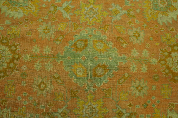 Low-pile rug detail showing a traditional medallion pattern in terracotta, sage green, and yellow.