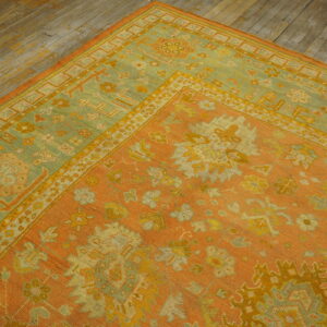 A low-pile rug with apricot, yellow, and faded green ornamental patterns rests on rustic wood flooring.
