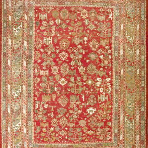Full view of a rich red rug with an intricate pattern of multi-colored geometric and botanical elements.