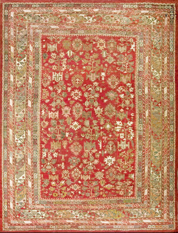 Full view of a rich red rug with an intricate pattern of multi-colored geometric and botanical elements.