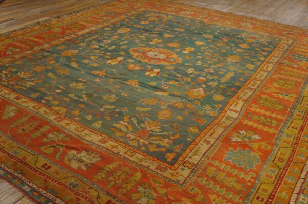 Ornate teal and orange area rug with floral patterns lying on light wood plank flooring.