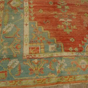 Close-up of a red and teal patterned rug with a medium pile on distressed wooden planks.