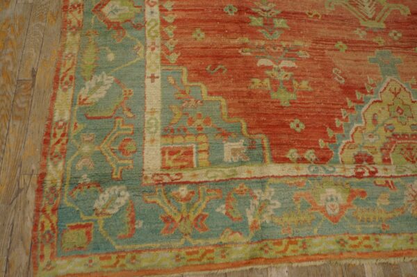 Close-up of a red and teal patterned rug with a medium pile on distressed wooden planks.