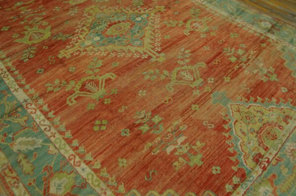 Low-pile rug with a distressed terracotta field and stylized floral patterns in seafoam and lime green.