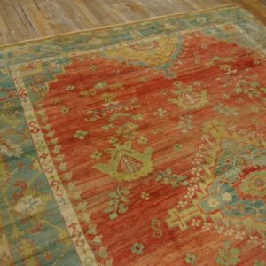 Distressed red rug with green and blue traditional motifs lies on rustic wood plank flooring.