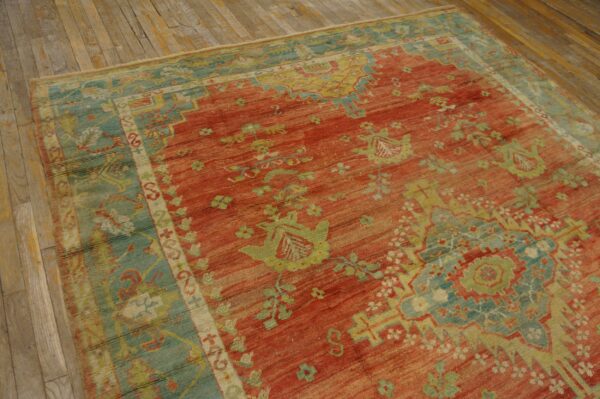 Distressed red rug with green and blue traditional motifs lies on rustic wood plank flooring.