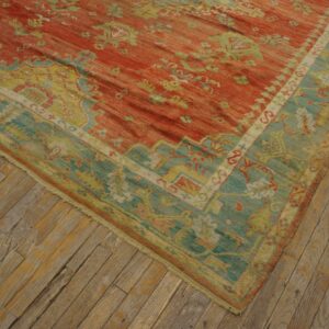 Distressed traditional rug in rust red and teal blue rests on rustic wooden floorboards.