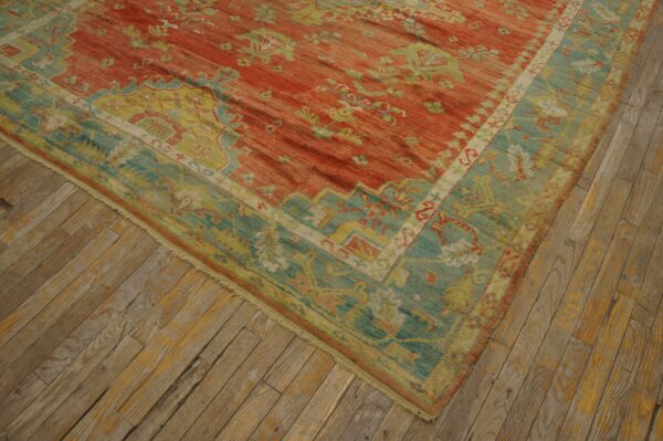Distressed traditional rug in rust red and teal blue rests on rustic wooden floorboards.