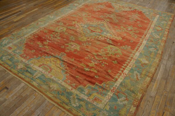 Red and teal traditional patterned rug lying flat on rustic wooden plank floors.