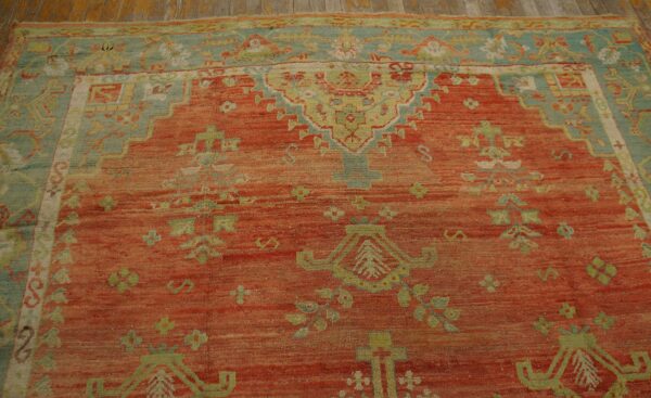 Orange and teal traditional rug with distinct abrash texture and geometric patterns on wood flooring.