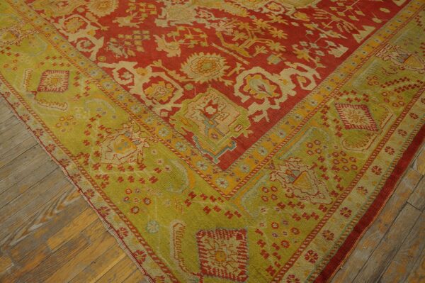 Rust-red and lime-green patterned rug corner featuring detailed geometric designs over distressed wood flooring.