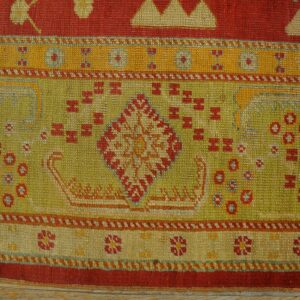 Geometric flatweave rug detail in red, chartreuse green, and gold colors over wood flooring.