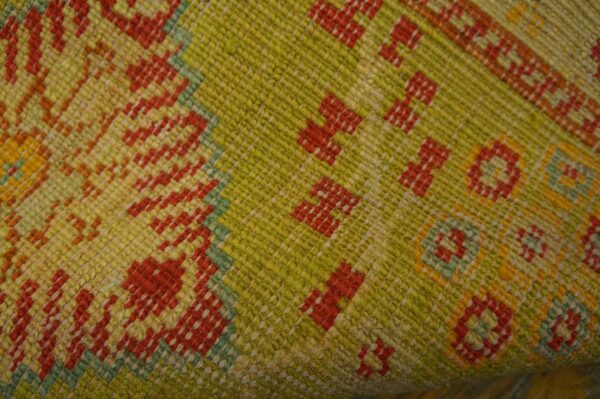 Textured flatweave rug detail in chartreuse, yellow, and red with small repeating geometric shapes.