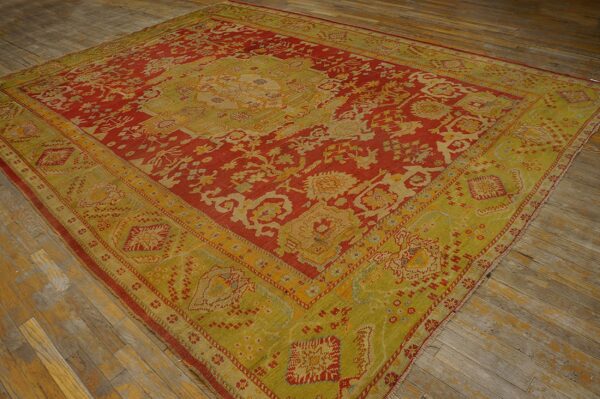 Ornate red and chartreuse rug displaying complex patterns rests on rustic, wide plank wood floors.