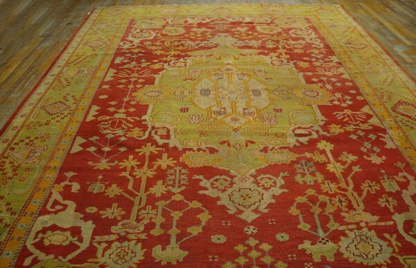 Traditional red and yellow-green rug with central medallion and borders displayed on rustic wood floor.