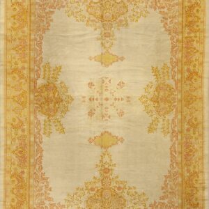 Ornate traditional rug featuring a cream field patterned with symmetrical yellow and peach floral designs.