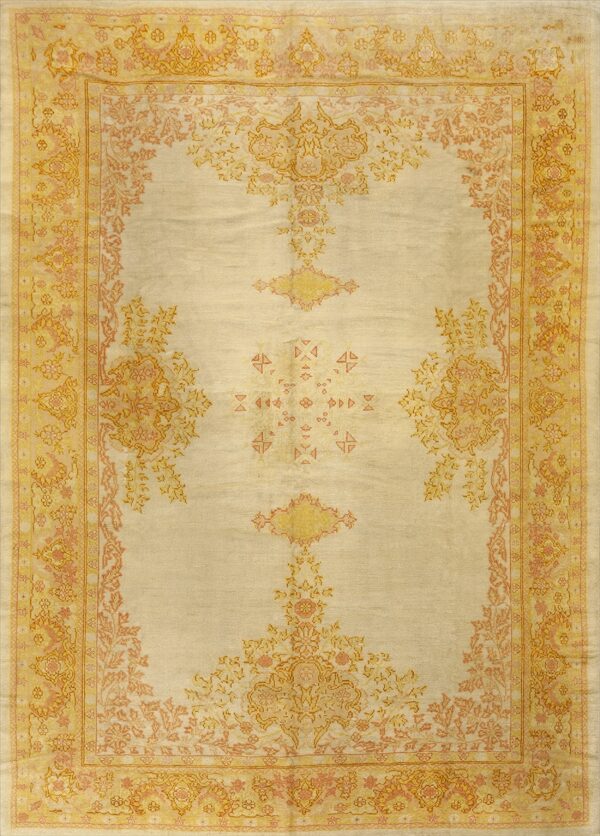 Ornate traditional rug featuring a cream field patterned with symmetrical yellow and peach floral designs.