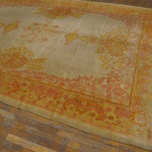 Low-pile area rug with faded botanical patterns in yellow, pink, and cream on rustic wood floors.