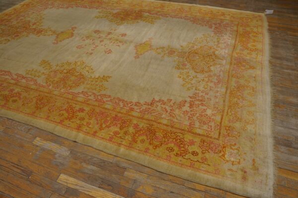 Low-pile area rug with faded botanical patterns in yellow, pink, and cream on rustic wood floors.