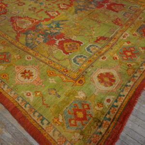 Traditional high-pile rug in green, red, and yellow with complex motifs on gray weathered hardwood flooring.