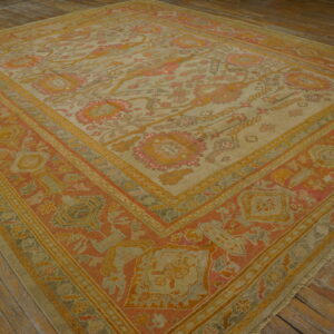 Ornate rug with muted orange, yellow, and beige colors covers rustic wooden floorboards.