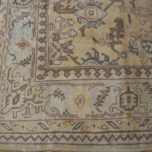 Traditional rug detail showing tan and pale blue panels with complex brown and taupe geometric patterns on wood floors.
