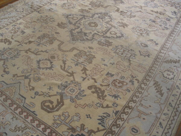Tan area rug with large-scale geometric designs in shades of taupe, gray, and brown.