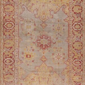 Traditional rug featuring a faded gray field, bordered by intricate patterns in deep red and distressed yellow.